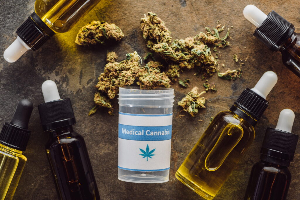Top view of medical cannabis container with amber dropper bottles of cannabis oil and dried flower buds representing terpene-rich full-spectrum cannabis products for wellness and therapeutic use